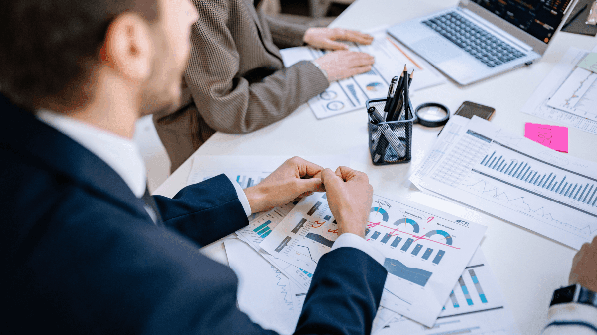 Profissionais da área financeira reunidos analisando gráficos e indicadores de desempenho.