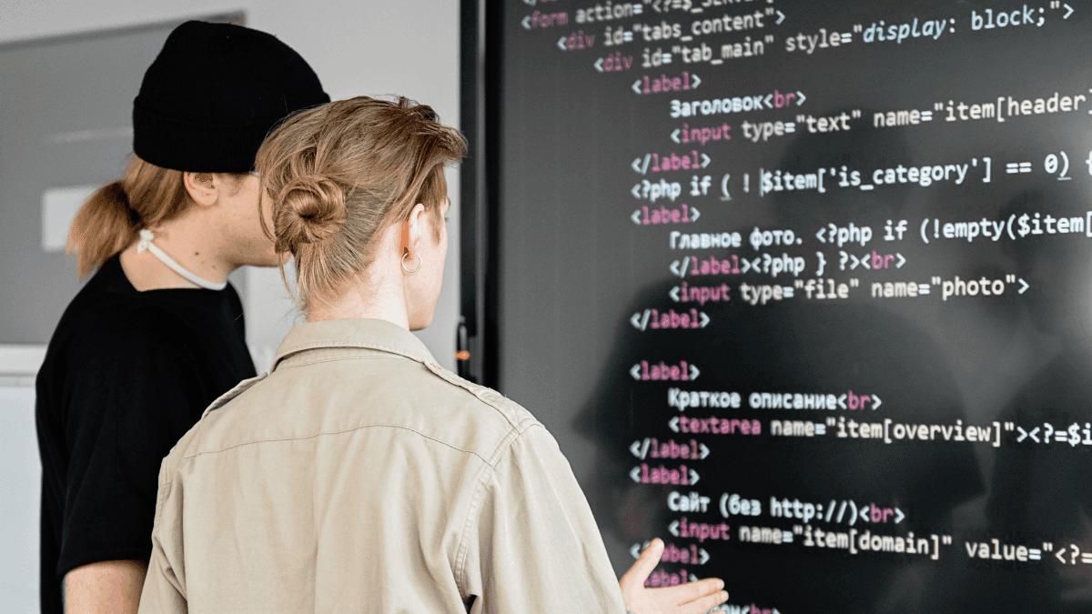 Dupla de jovens debatendo em frente a um telão com códigos sobre inteligência artificial e tecnologia